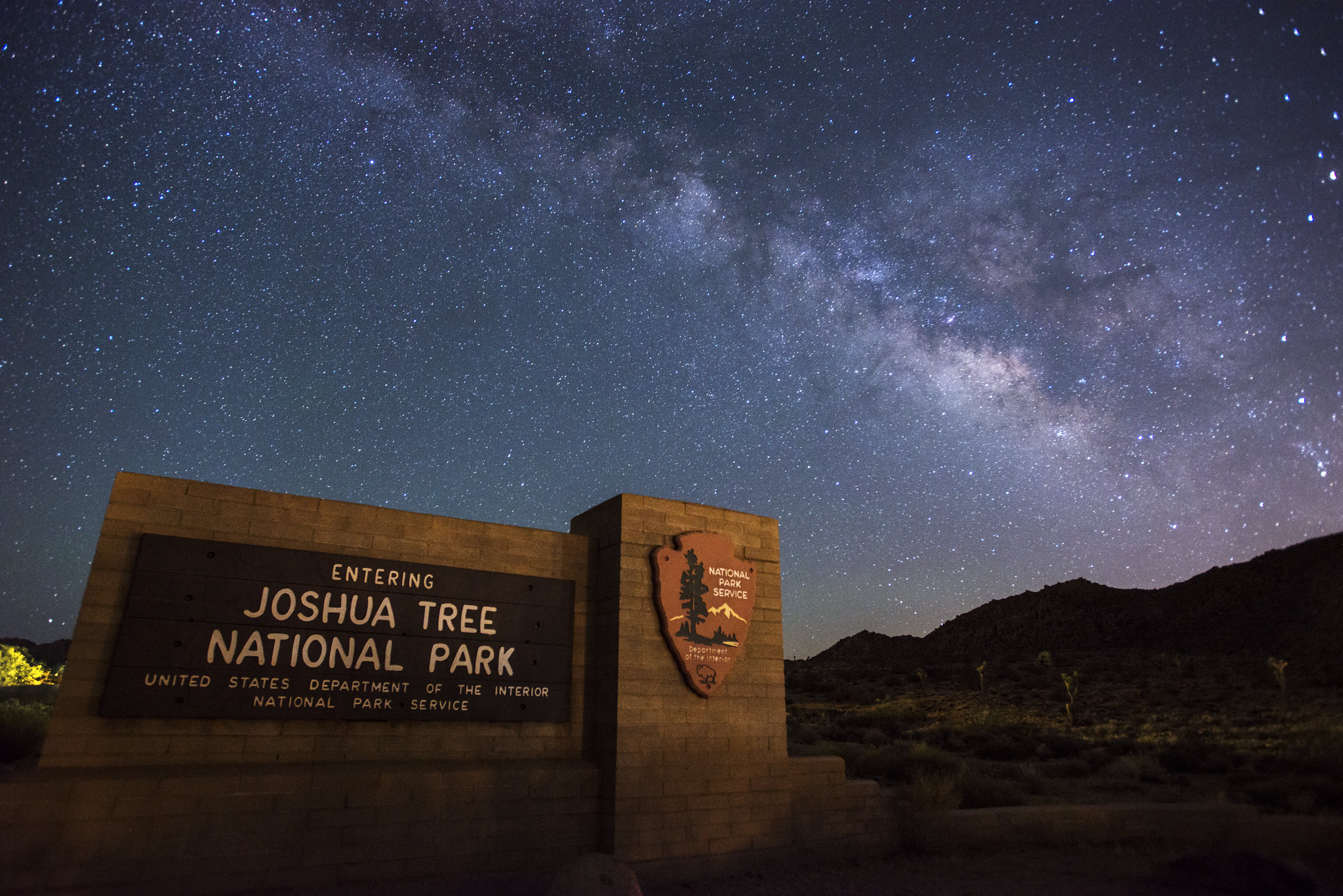 Park Entrance sign illuminated with many stars and the milky way in the backdrop