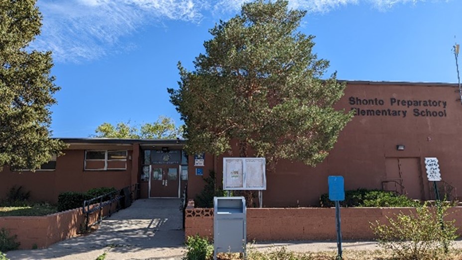 Brown school building with trees and ramp to the front door.