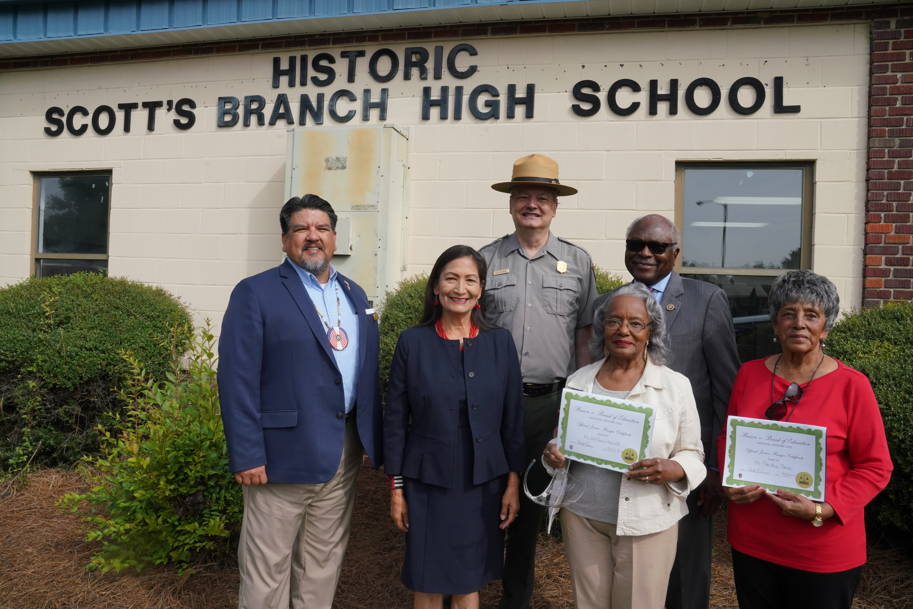 Secretary Haaland and five others stand in front of Historic Scott's Branch High School. 