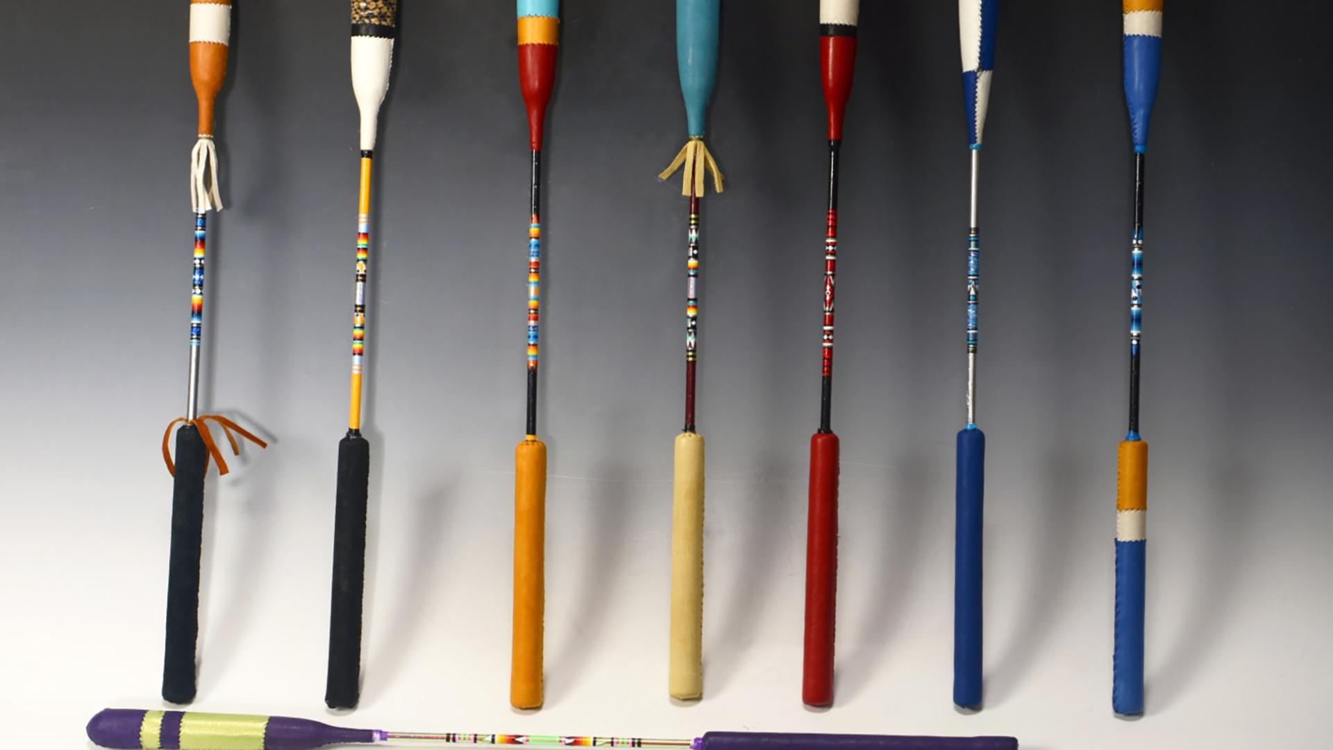 A row of multi-colored drumsticks against a grey background.