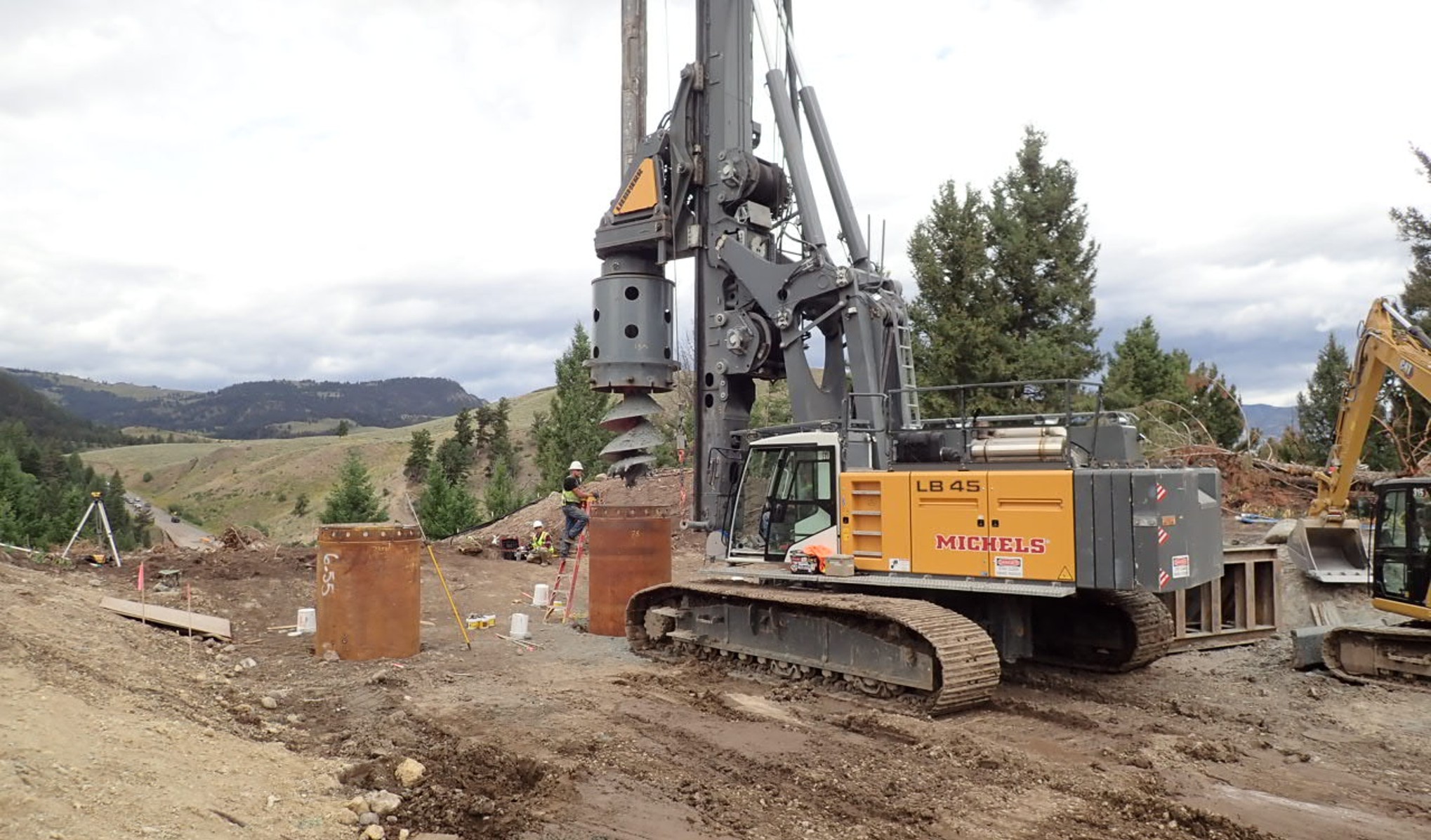 Yellow construction machinery at work to build the foundation of the new bridge