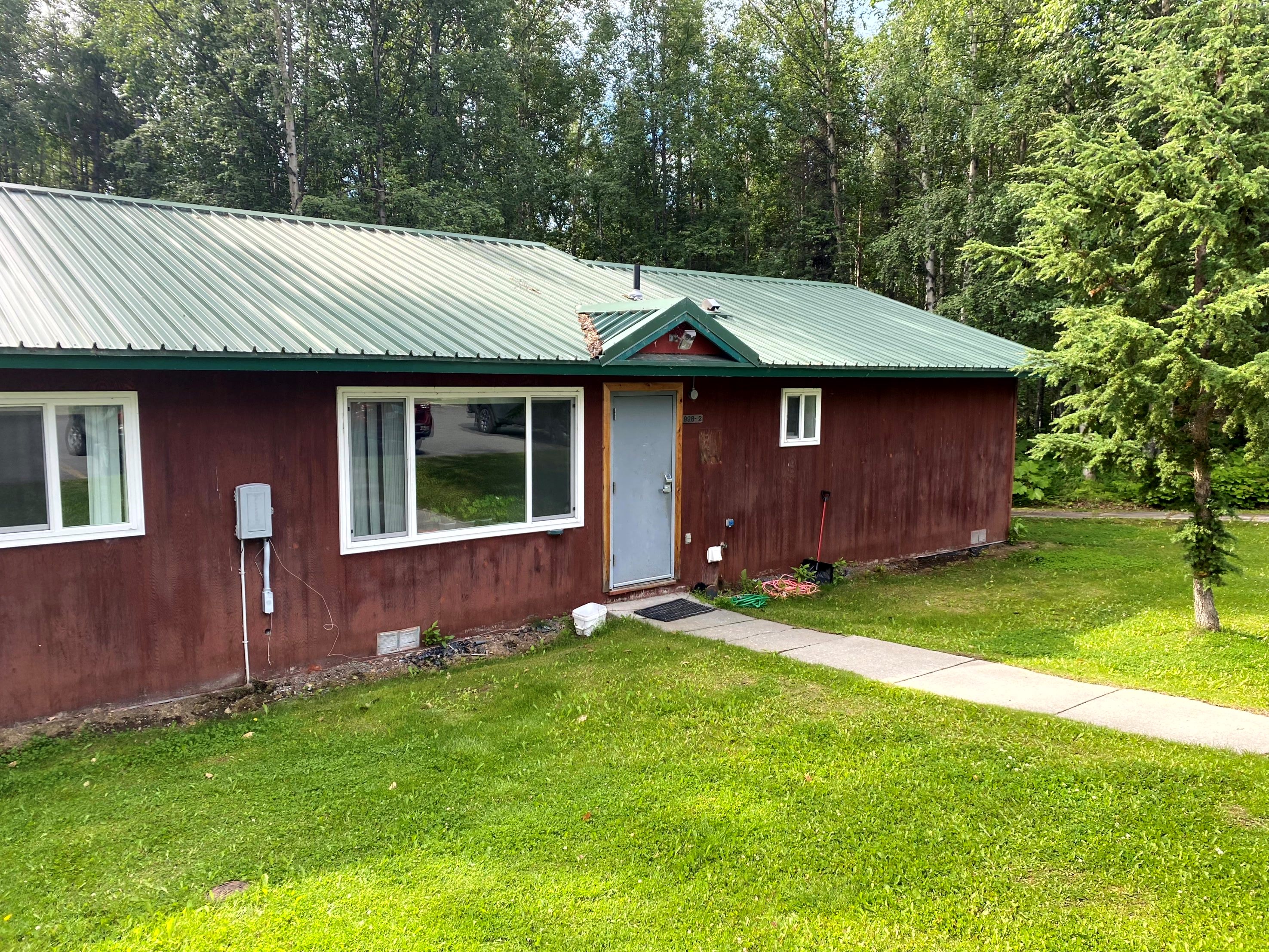 Bunkhouse with plywood siding painted red and green roof. 