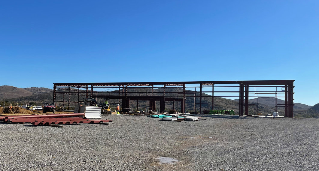 Building frame sits on rocky ground surrounded by construction equipment.