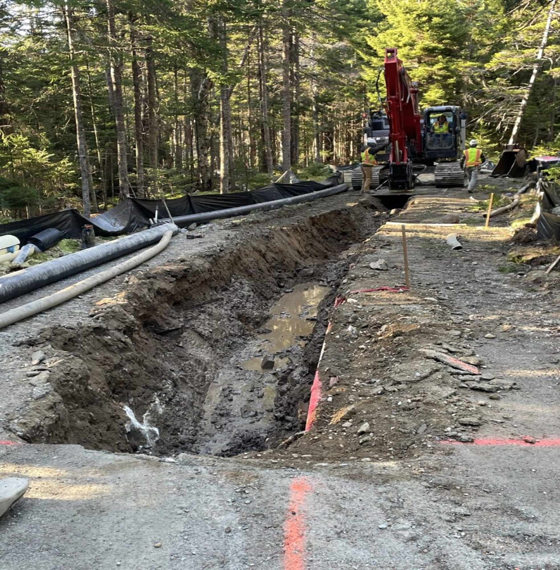 Construction crew drills a hole along a cement road to install a water line.