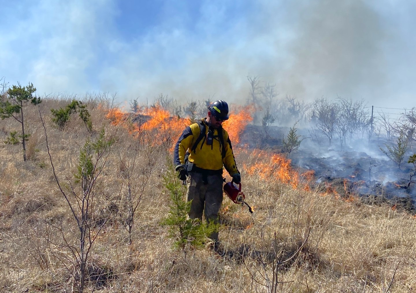 A wildland firefighter conducts a prescribed burn with a drip torch. Photo by Josh Williams BIA