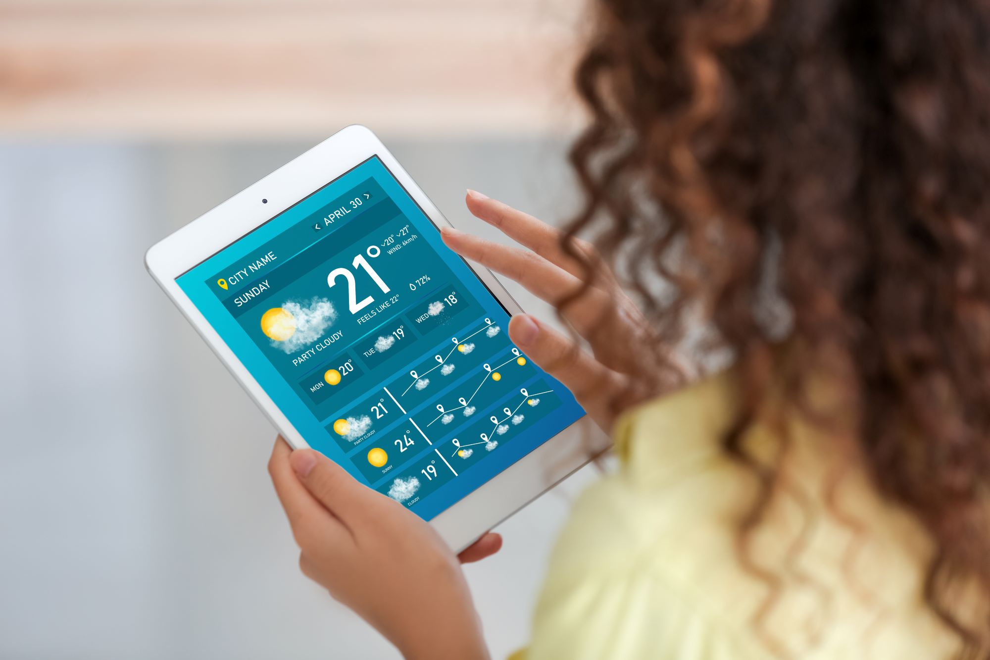 A woman holds a tablet as she looks at the latest weather conditions.