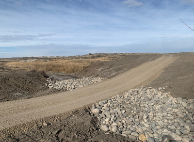 Dirt road surrounded by rocks at its lowest point.
