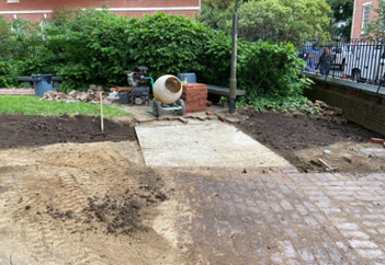 Construction site with brick patio surrounded by dirt.