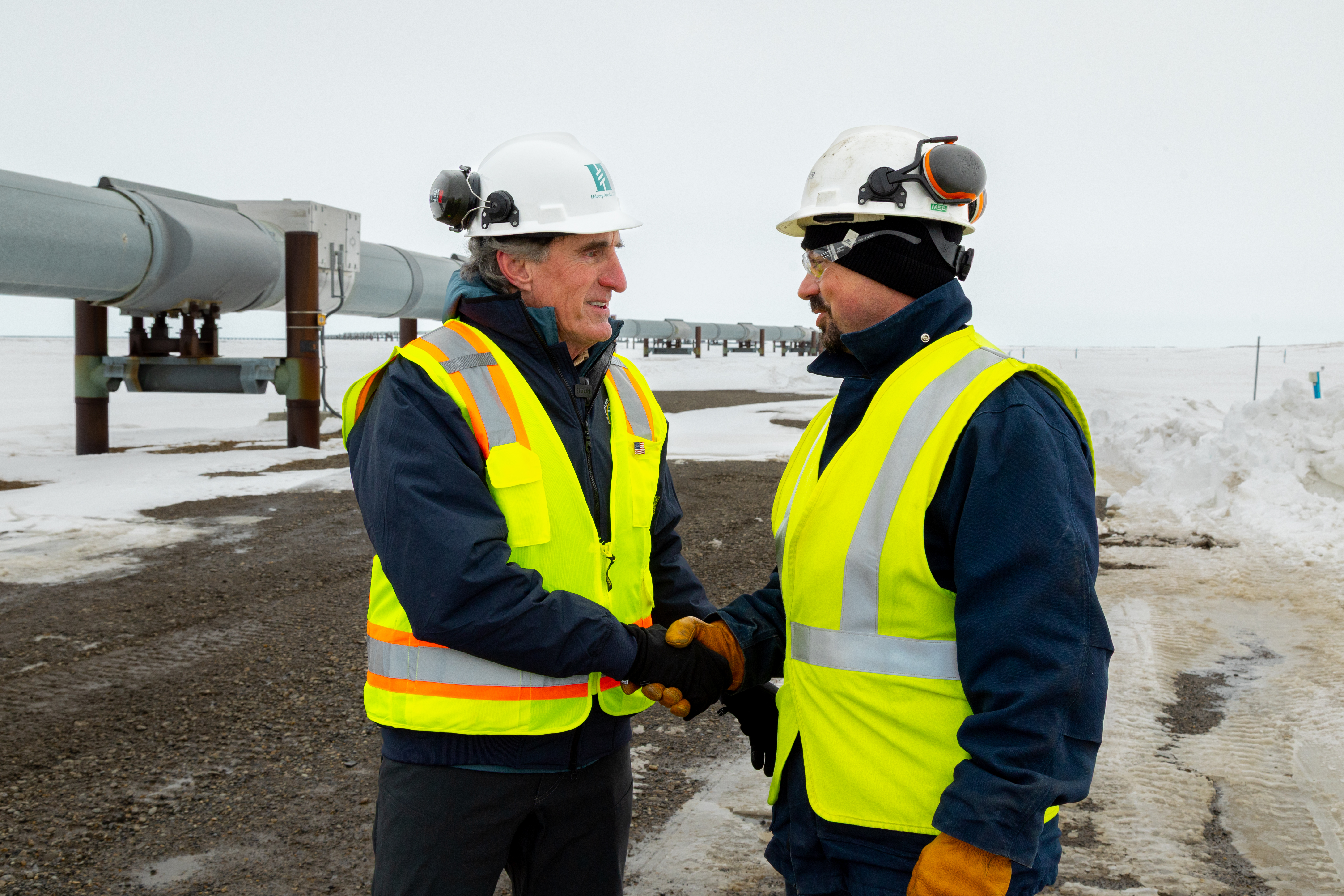 Secretary Burgum shaking hands with man in safety vest at Alaska pipeline