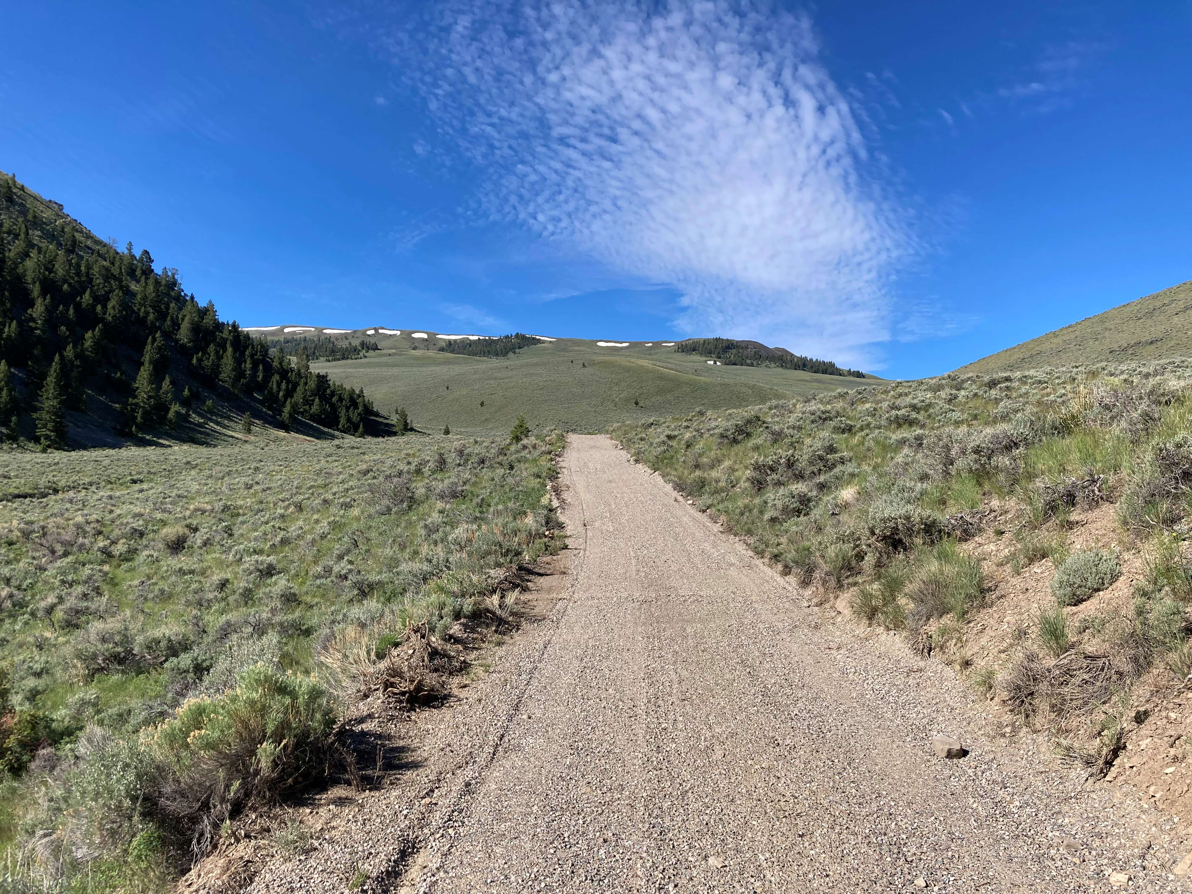 Aggregate road surrounded by green hilly landscape.