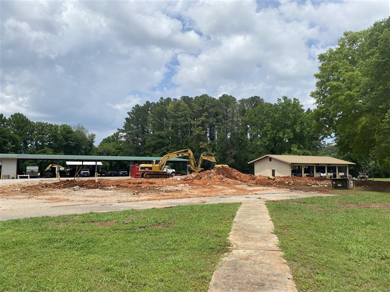 An excavator moves a large pile of rubble and dirt on a concrete lot.