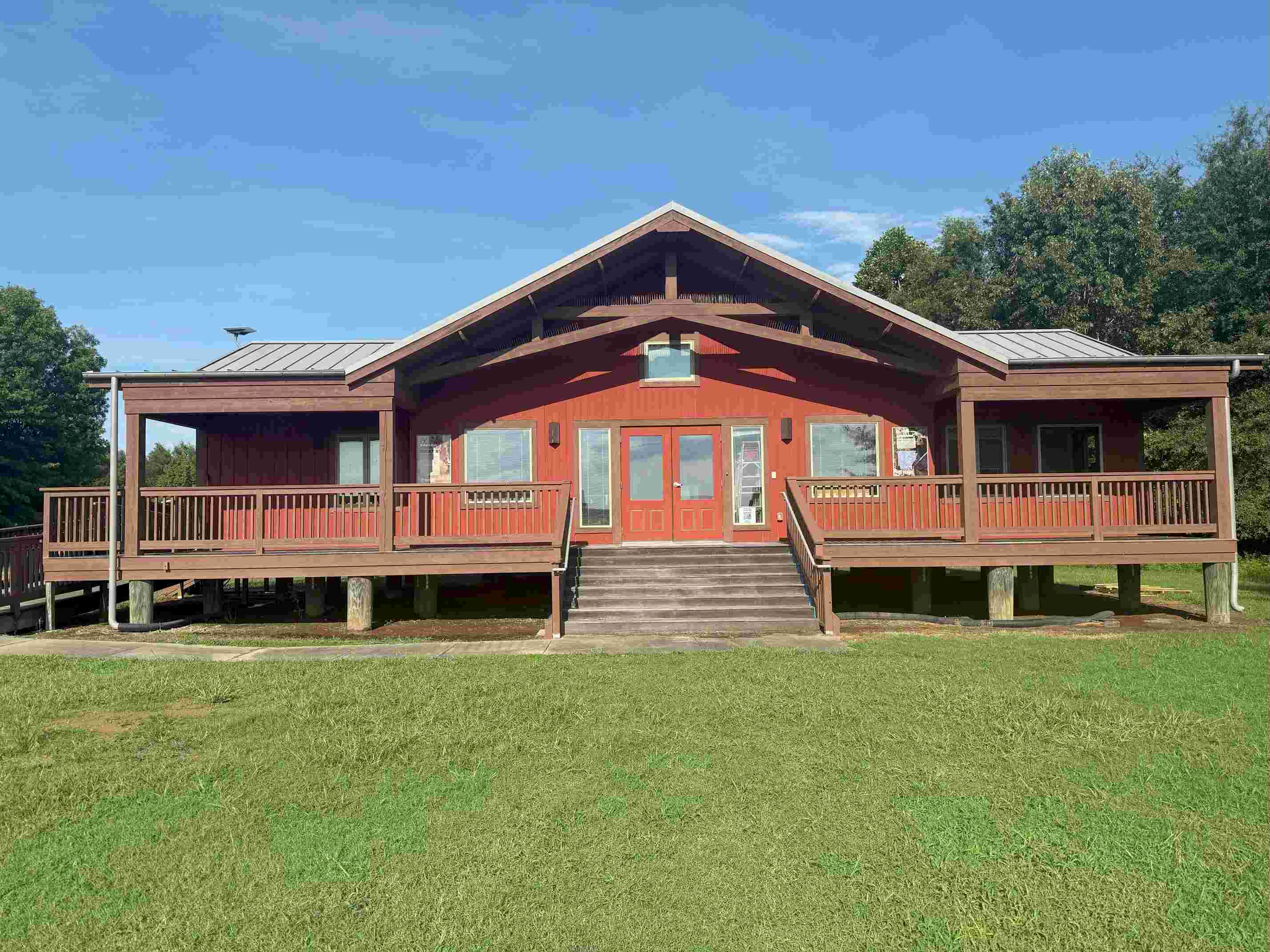 Red painted visitor center elevated on stilts with a large porch and stairs.