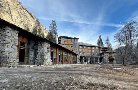 Exterior view of a completed dining center with stone walls and timber accents, set against a mountainous landscape.