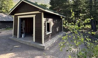 New generator building with brown siding sits next to forested area