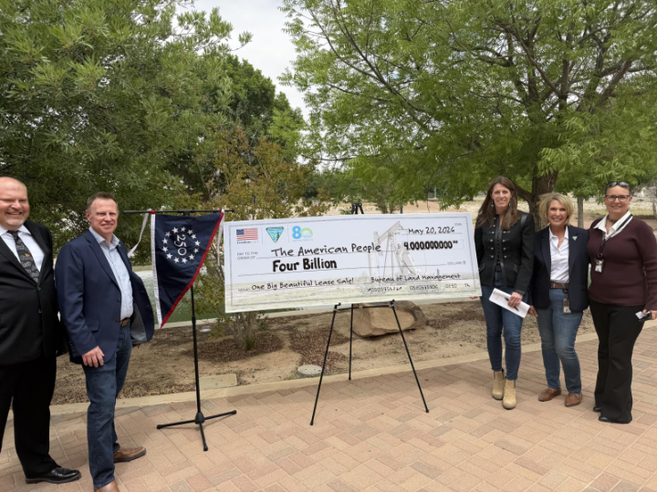 Group of people standing next to large check. 