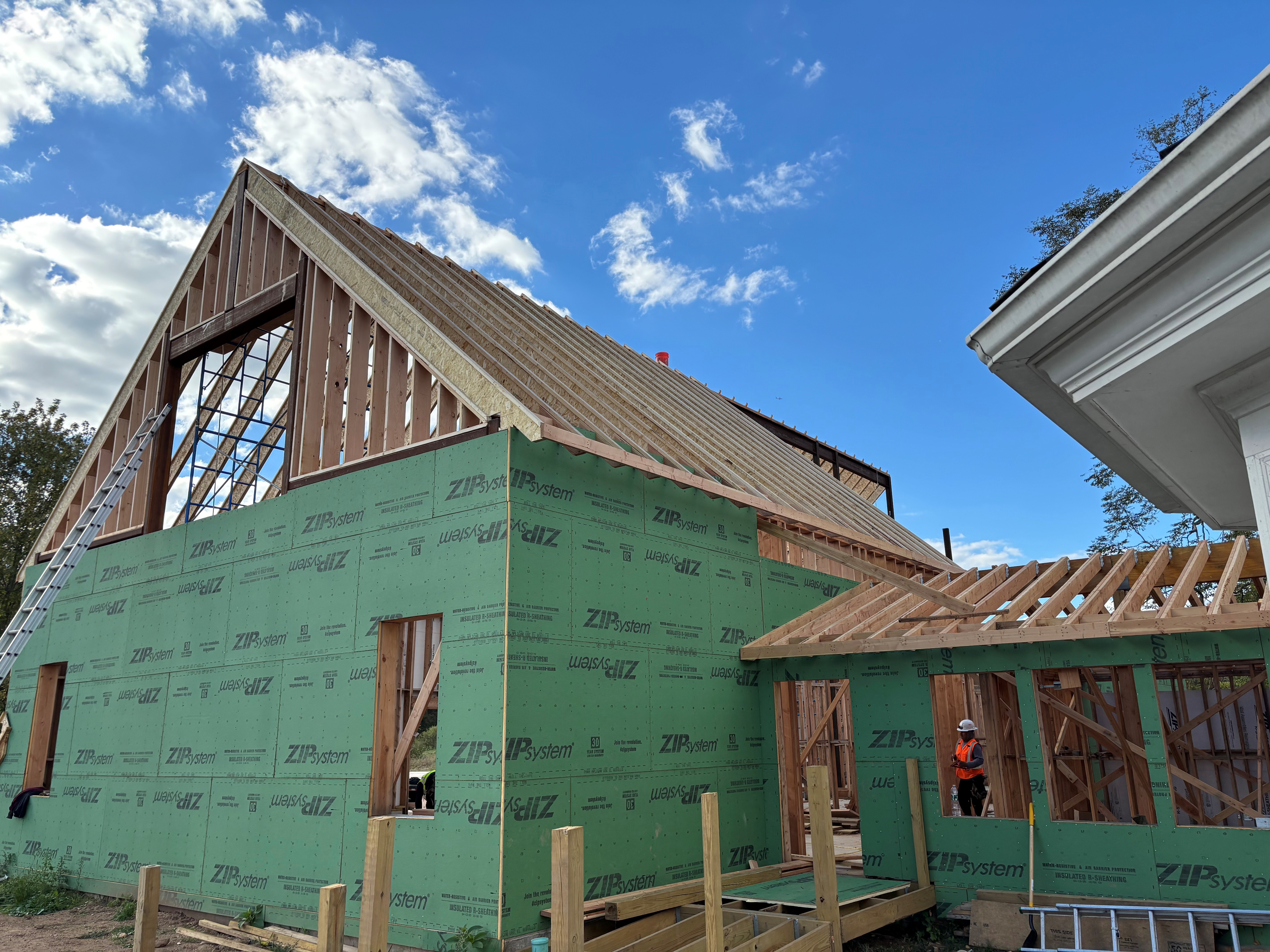 Building under construction with exposed wooden framing and green sheathing.