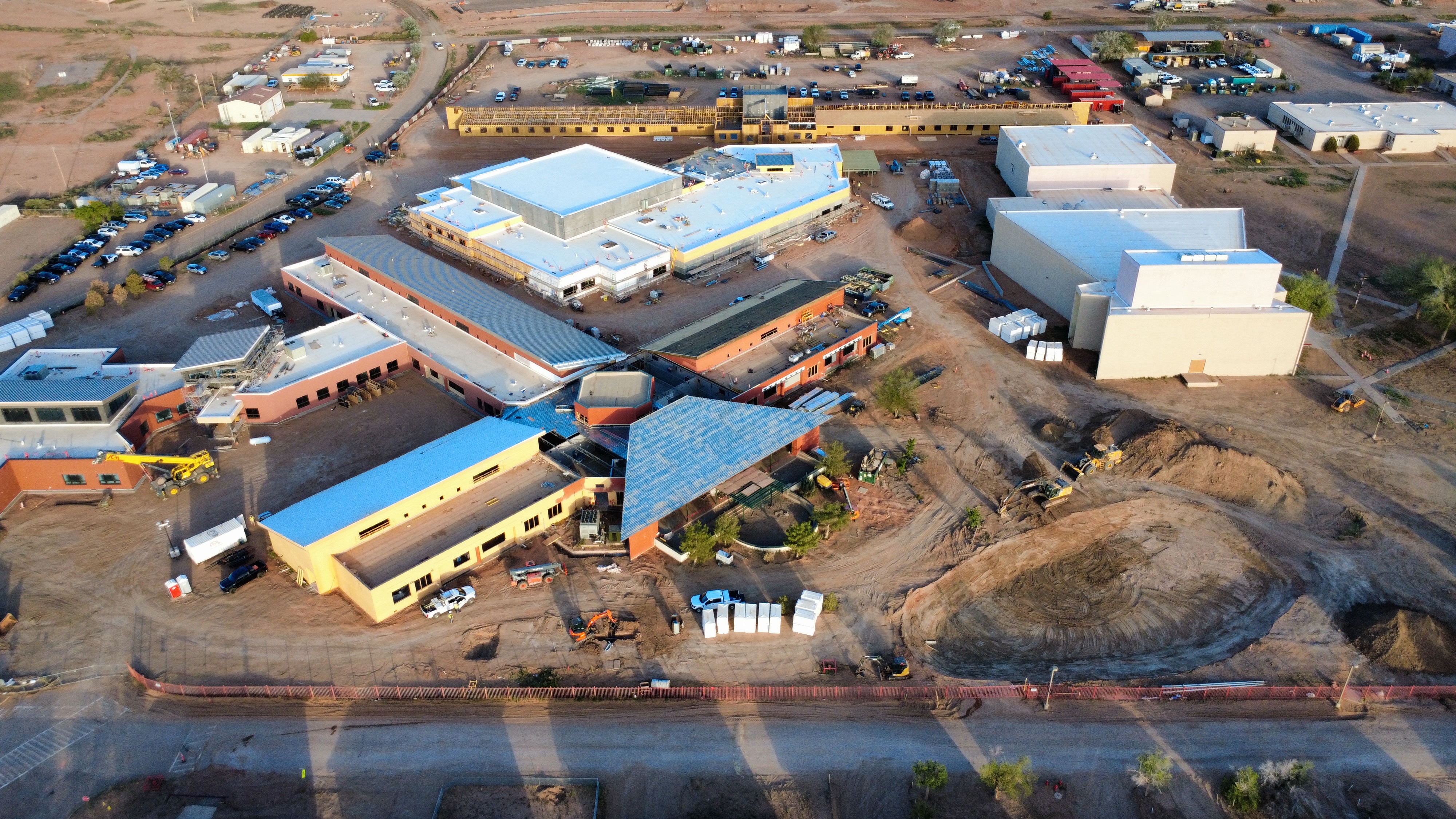 Aerial view of a multi-building campus under construction in a desert landscape.