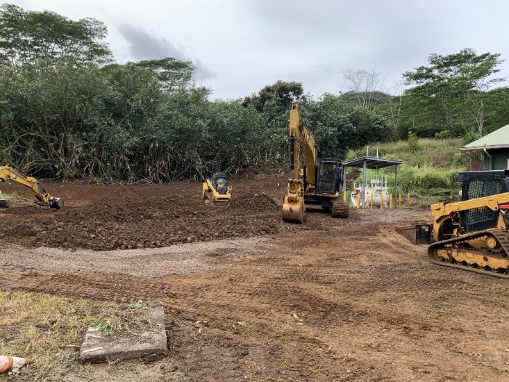 Excavation and site grading underway with heavy equipment, including excavators and compactors.