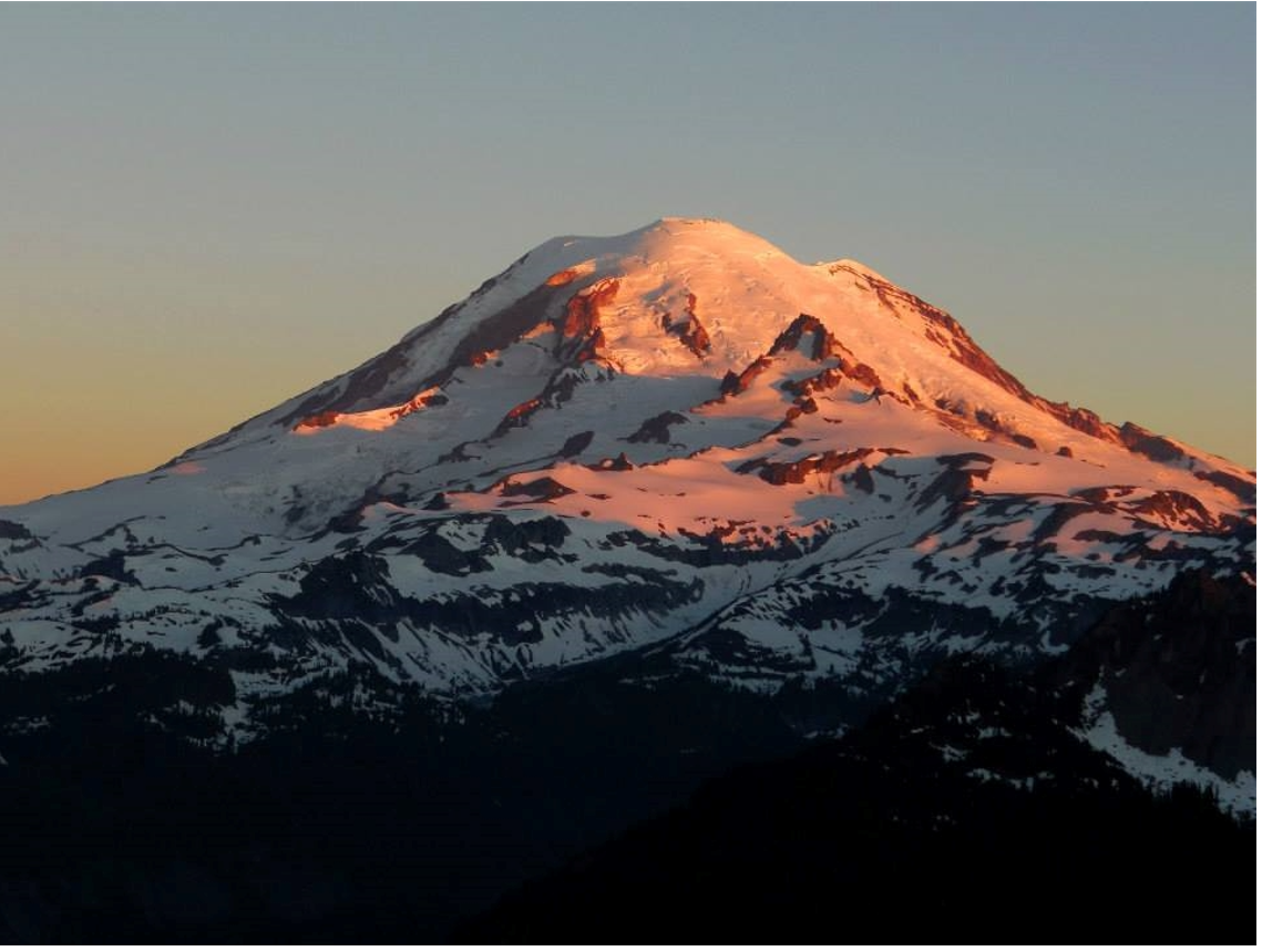 Early morning light paints Mount Rainier in golds and pinks.