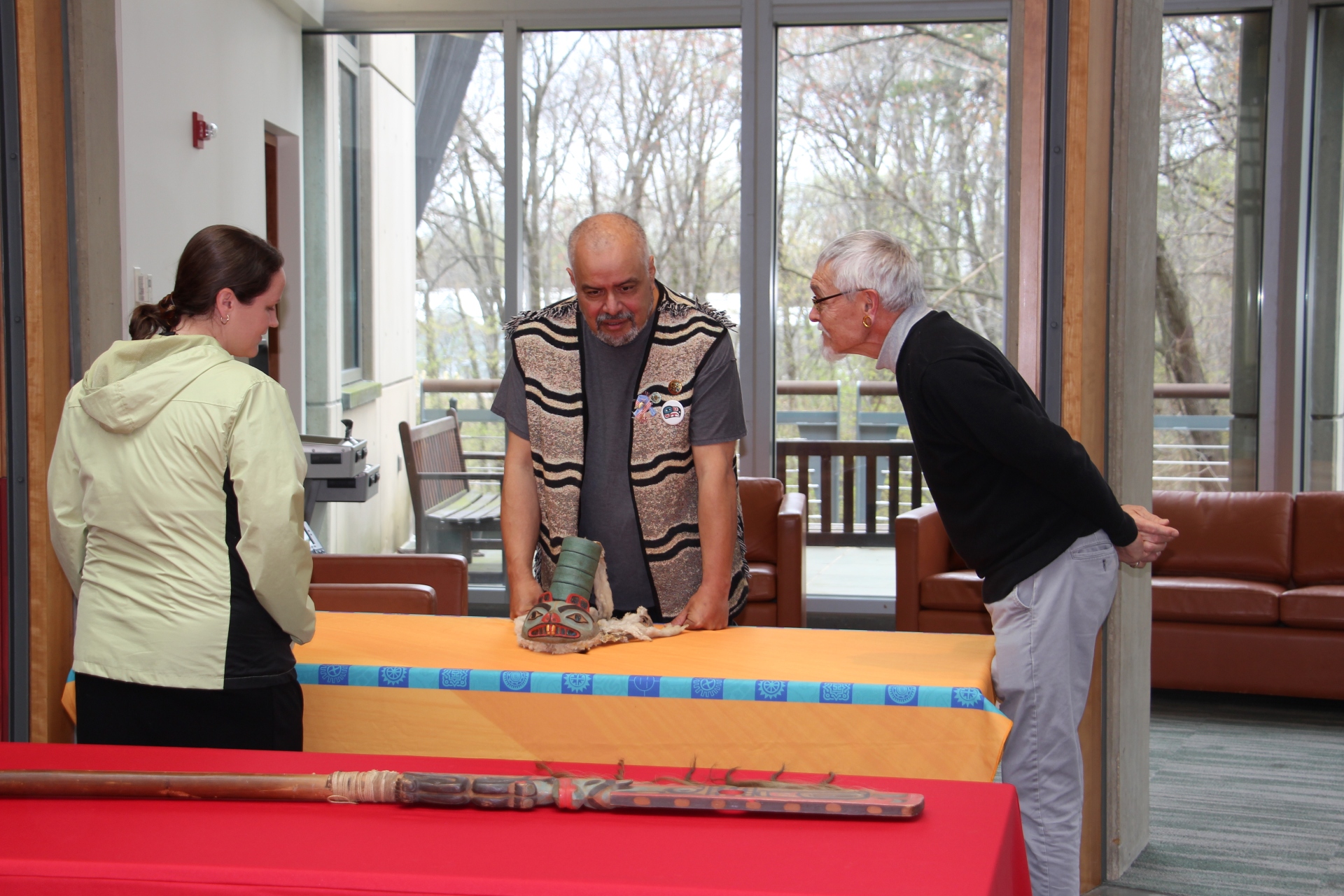 Two men standing at a table with Tlingit clan hat during a repatriation ceremony. 