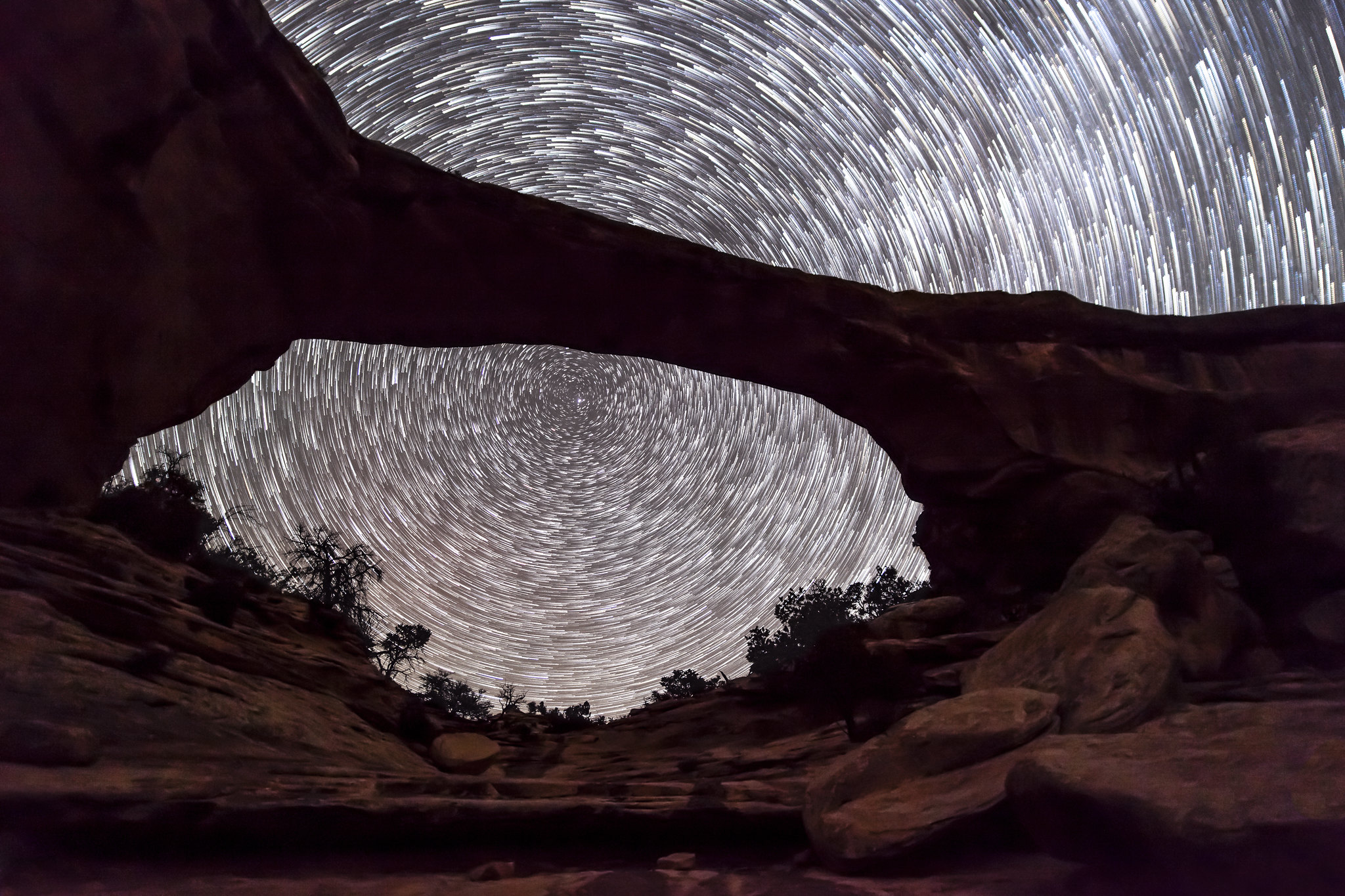 Stars whirl behind the silhouette of Owachomo Bridge at night.