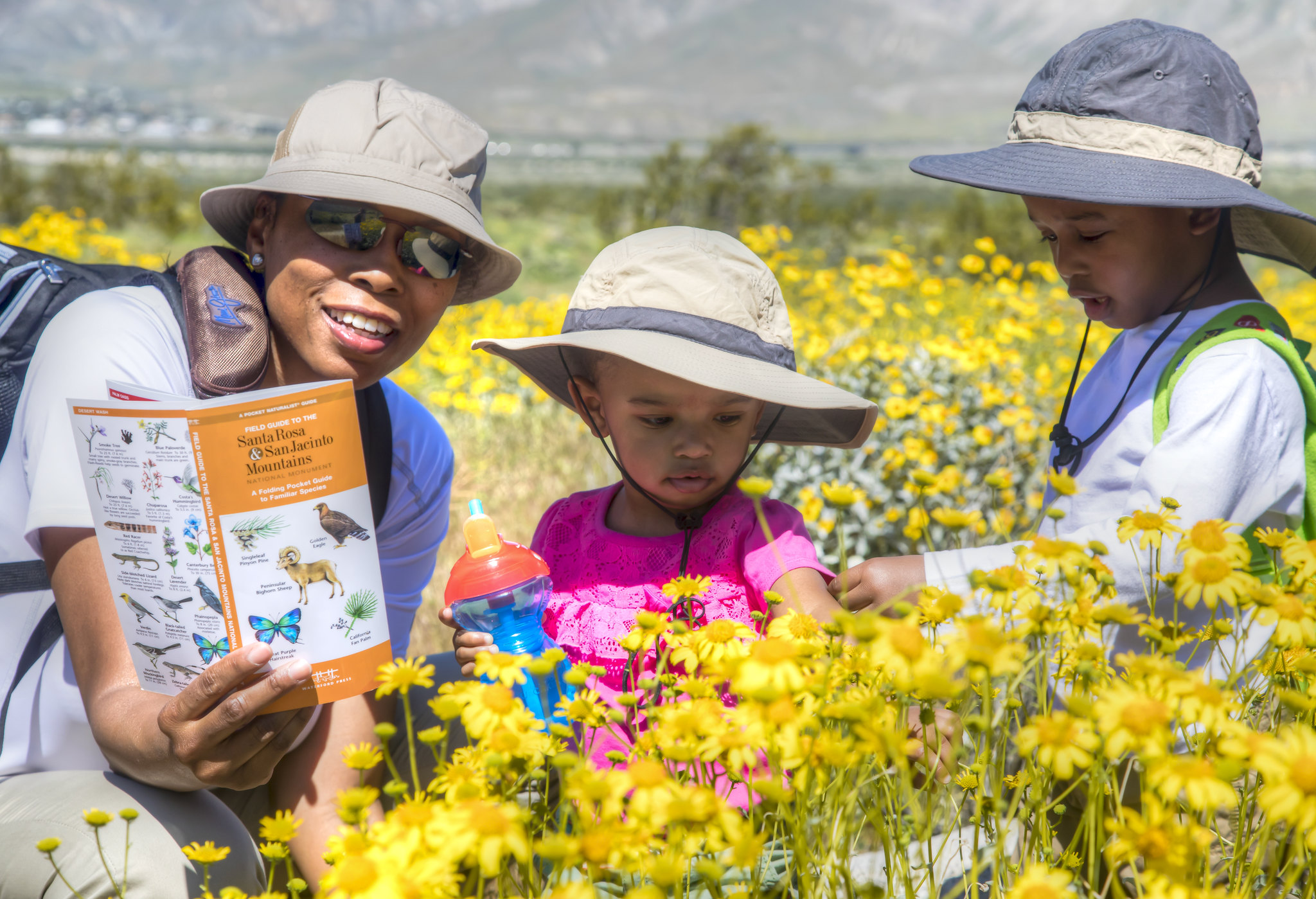 Adult and two kids in a field of yellow flowers. 