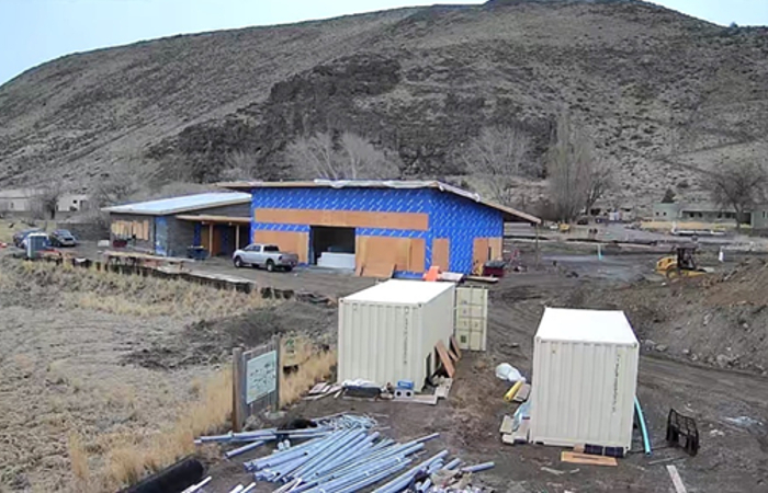 Unfinished structure on the side of a dirt hill surrounded by construction pieces.