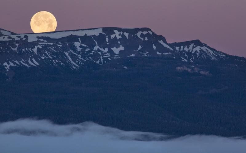 Full moon in a purple sky over the sun-covered Centennial Mountains.