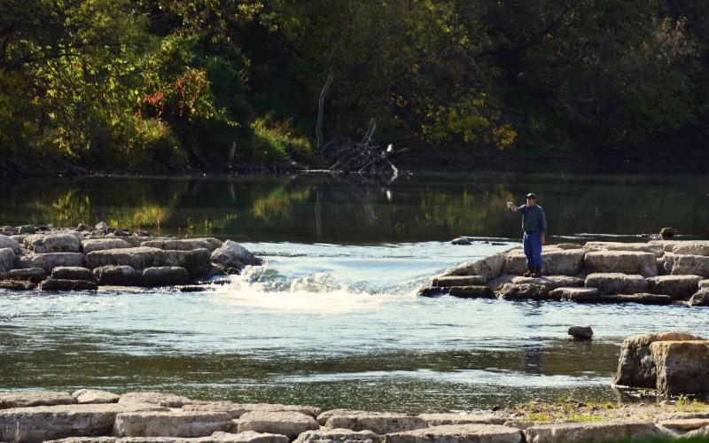 Person fly fishing on a rushing river.