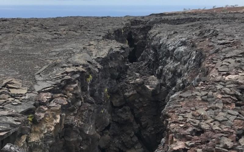 A large crack appears in the rocky ground