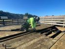 A construction worker removes a deteriorated wooden board on an observation deck.