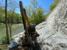 A construction vehicle works on repairs at the base of the historic dry stone retaining wall.