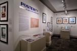 View of a museum exhibition gallery with a title and intro panel with vitrines