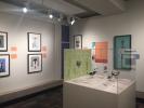 A vitrine with several small models of birds and gallery walls with interpretive panels and six works of art