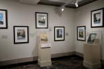 Gallery view of the "POSTERity" exhibition at the Interior Museum, showing six framed works and two serigraphs in vitrines