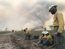 Jackson Hotshots beside a road with smoke billowing in the background.