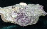 Closeup of a flourite telluride (a grey and purple rock) sample.