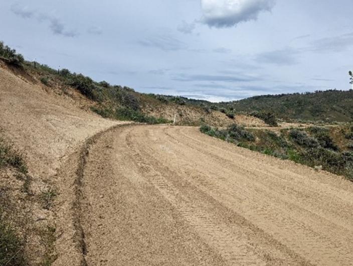 Newly repaired dirt road winds through hilly landscape.
