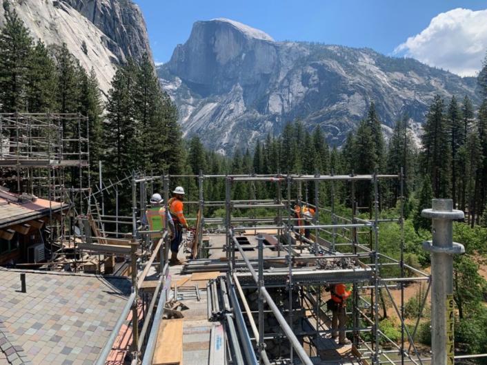 Scaffolding surrounds the exterior of the Ahwahnee Hotel with Half Dome in the background.