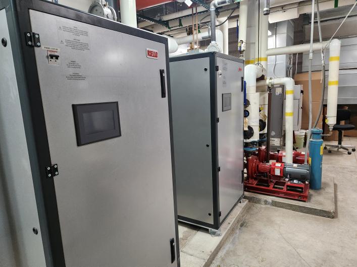 Grey boiler units in a boiler room. 