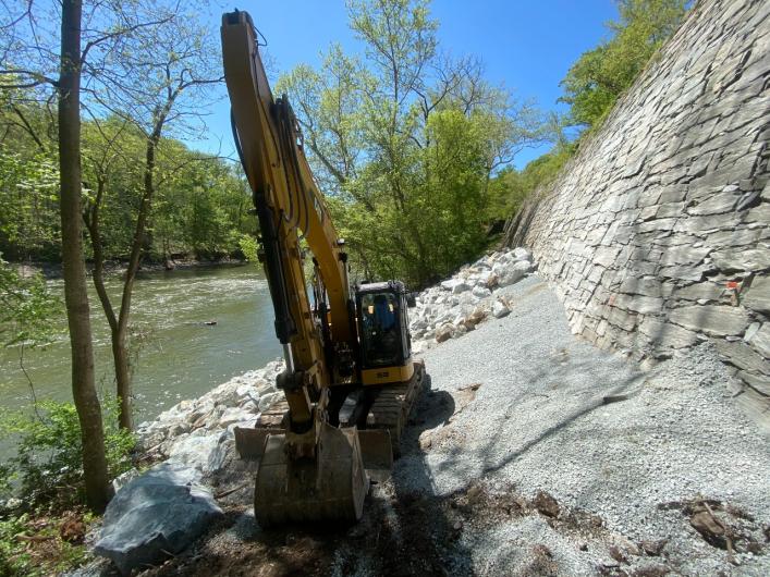 A construction vehicle works on repairs at the base of the historic dry stone retaining wall.