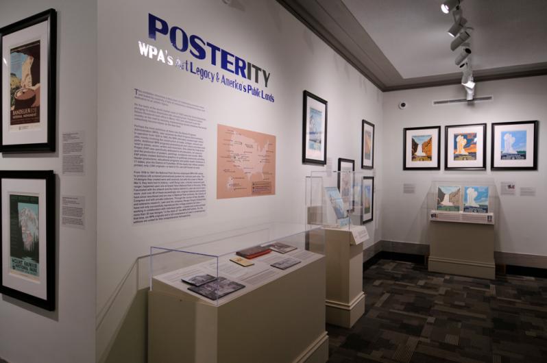 View of a museum exhibition gallery with a title and intro panel with vitrines