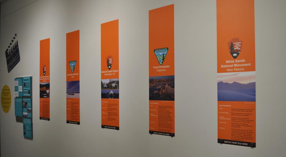 Section of the exhibition entitled, "On Location" consisting of five vertical panels and a magnetic tile-matching game.