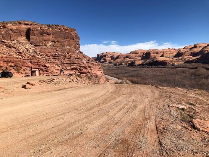 Dirt road cleared of surface hazards winds through hilly landscape.