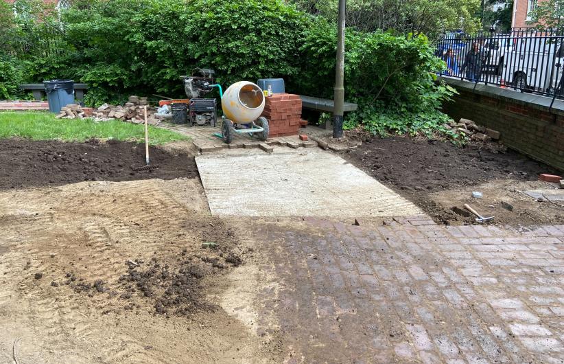 Construction site with brick patio surrounded by dirt.