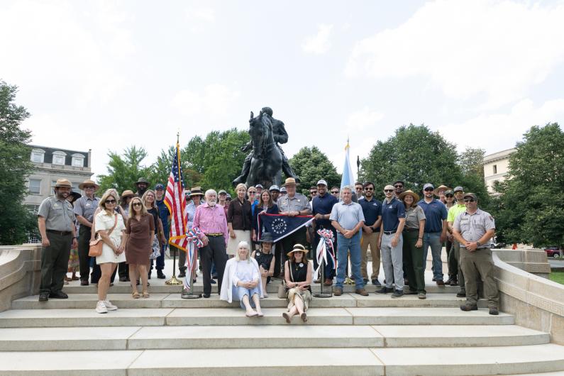 Group of people with 250 flag in front of Sheridan Fountain Ribbon Cutting