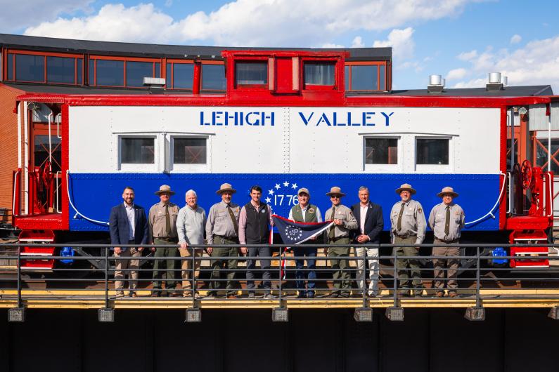 Group of people holding 250 flag in front of steam train