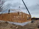 Construction crew builds wooden frame for new fire station barracks.