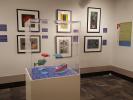 Gallery view with six Charley Harper serigraphs and a vitrine with models of fish.
