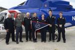 Group of people holding commemorative flag in front of helicopter on an oil rig. 